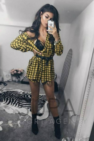 Cara dressed up showing her black lingerie wearing yellow and black pattern dress taking selfie 