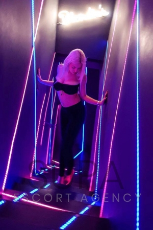 Naomi walking up stairs in nightclub wearing black bra and black pants in high heels 